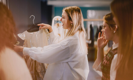 A woman examines various clothing items hanging on a rack